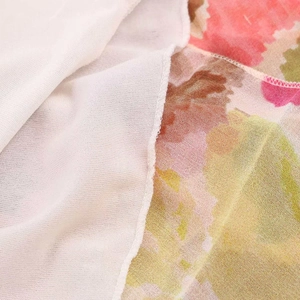 Close-up detail of floral print fabric with high-quality white overlock stitching and soft texture