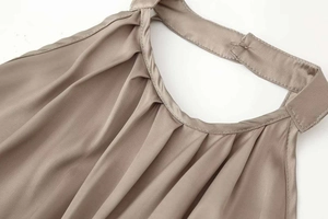 Detailed close-up of taupe satin halter top neckline with elegant pleated textures