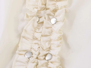 Detail of ruffle trim and silver metal buttons on beige summer short sleeve shirt
