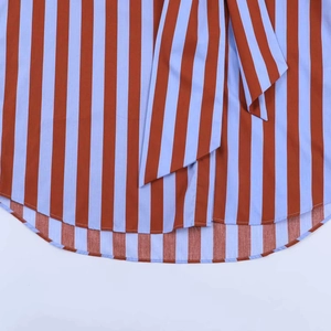 Detailed close-up of blue and red vertical stripes fabric with a curved hemline finish
