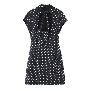 Detail of black polka dot mini dress featuring a bow tie neckline and chest cutout design