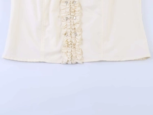 Detail of ruffle trim blouse showing ruffled edges and metallic silver round buttons