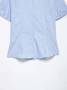 Detailed view of the light blue poplin shirt hemline with precise stitching and slim cut