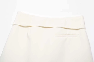 Detailed close-up of high-waist white skirt featuring a wide waistband and piping pocket
