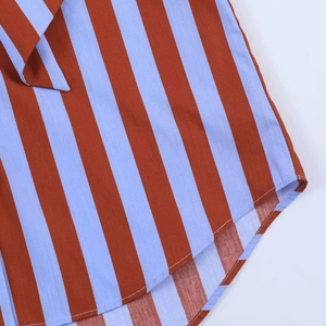 Detail of blue and red striped fabric showing the curved hem and high-quality stitching