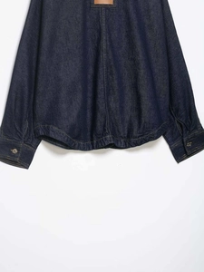 Detail of dark blue denim shirt with leather patch and contrast yellow stitching