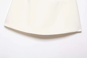 Macro view showing the textured hem of a white high-waisted A-line skirt with neat edges