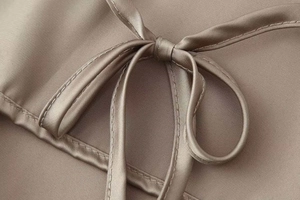 Detail of elegant champagne satin bow tie and refined stitching on the halter neck top