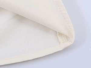 Macro shot of precise interior seam and hem on an off-white cotton blend blouse