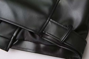 Détail d'une veste en similicuir noir montrant les coutures de précision et le passant