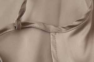 Detail view of smooth taupe satin fabric with clean stitching and thin shoulder strap