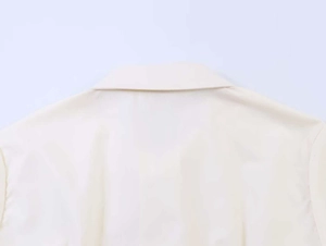 Detailed close-up of light beige short sleeve shirt with classic collar and smooth fabric