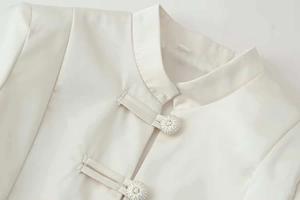 Close-up of off-white jacket featuring Mandarin collar and traditional frog button closure