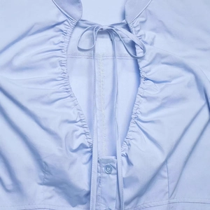 Light blue poplin shirt featuring pleated texture, neckline ties and resin button detail