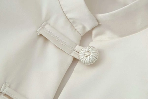 Detail of mandarin collar with traditional handmade knot buckle on cream satin jacket