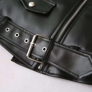 Détails d'une veste en cuir noir avec ferrures métalliques argentées et boucle de ceinture