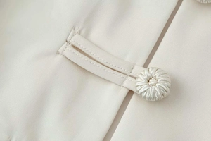 Macro detail of high-quality cream fabric with traditional handmade knot button detail