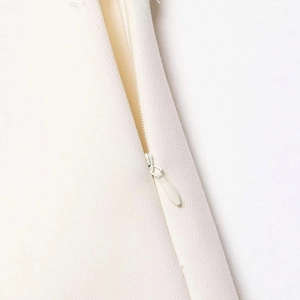 Detail of white high waist A-line skirt featuring hidden zipper and twill fabric texture