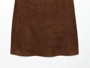 Dettaglio dell'abito marrone scamosciato che mostra l'orlo del tessuto e il drappeggio