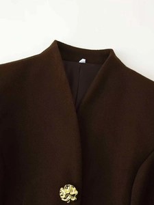Detail of a dark brown wool coat collar with a large textured gold vintage metal button