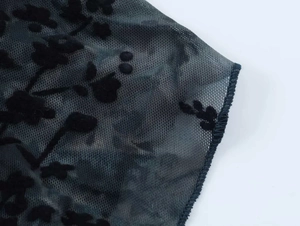 Dettaglio del tessuto a rete nero trasparente con motivi floreali floccati vintage