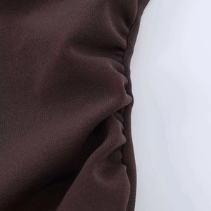 Detail of dark brown ruched stretch fabric showing soft knit texture and side pleats