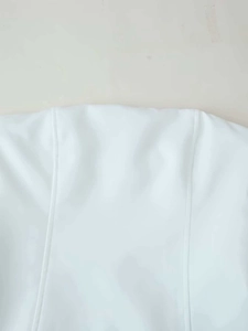 Close-up of white garment showing precise princess seam stitching and fabric texture