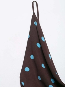Detailed view of summer camisole with large blue polka dots on a brown background fabric