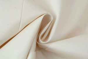 Macro shot of ivory satin jacket fabric showing smooth texture and luxury silk gloss