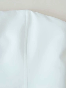 Detailed close-up showing the vertical seam and texture of the white stand-collar top