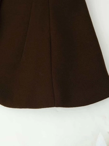 Close-up of premium dark brown wool fabric texture and pleated hem of the skirt