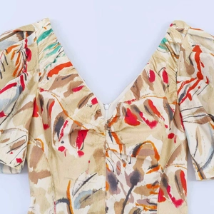 Detail view of V-neckline with ruched chest and colorful abstract floral print