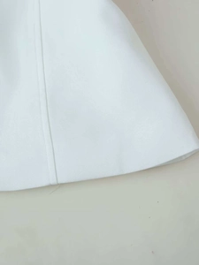 Close-up of white garment fabric texture with professional stitching and hemline detail
