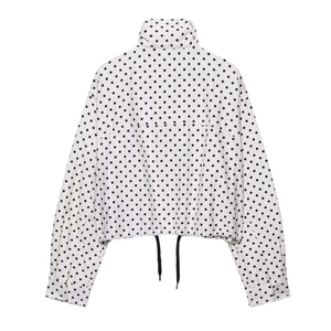 Détail de la veste à pois avec col montant et cordon de serrage réglable à la base