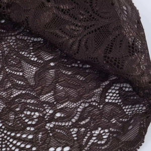 Detailed close-up of brown floral lace fabric with intricate cutout patterns