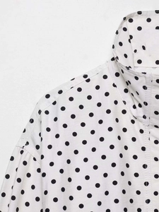 Détail rapproché du chemisier blanc à pois montrant le col et la qualité des coutures