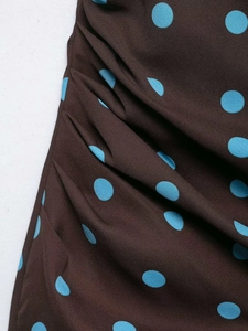 Detail of brown polka dot dress fabric with blue dots and ruched side pleating texture
