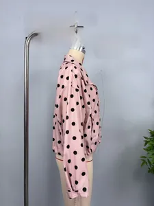 Detailed view of pink jacket with black polka dots featuring elastic cuffs and hemline
