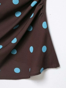 Close-up of brown and blue polka dot fabric showing soft texture and hem stitching