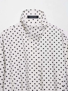 Détail du col montant et du cordon de serrage sur la veste blanche à pois noirs