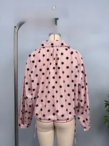 Detailed macro view of pink long sleeve shirt with black polka dots and stand collar