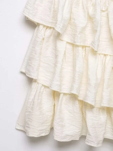 Detail of cream tiered ruffle dress showing pleated chiffon texture and layered design