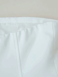 Detail shot of clean white woven top showing precise overlock stitching and seams