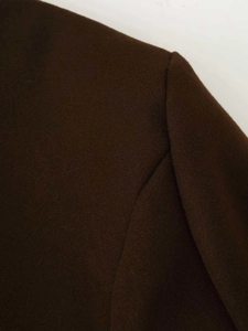Macro detail of dark brown wool coat shoulder showing high-quality textured fabric seams