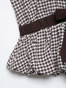 Detailed view of brown gingham top featuring elastic smocked waist and side bow tie detail