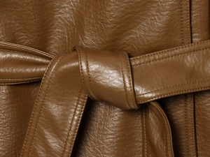 Détail de la texture en similicuir marron et couture de la ceinture sur le trench-coat court