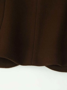 Close-up of the hem stitching and thick wool fabric texture on a dark brown skirt