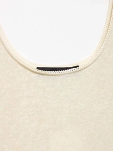 Detailed close-up of cream knit dress neckline with elegant picot edge trim