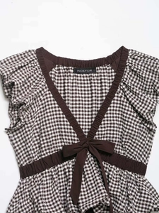 Detailed macro view of brown gingham fabric texture and front bow tie on V-neck blouse