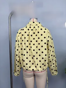 Detailed view of yellow polka dot jacket with adjustable drawstring hem and pleats
